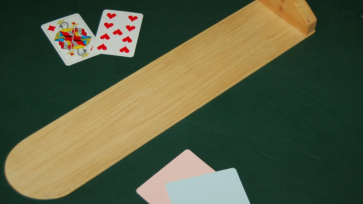 Baccarat paddle and dealt cards on green baccarat table felt