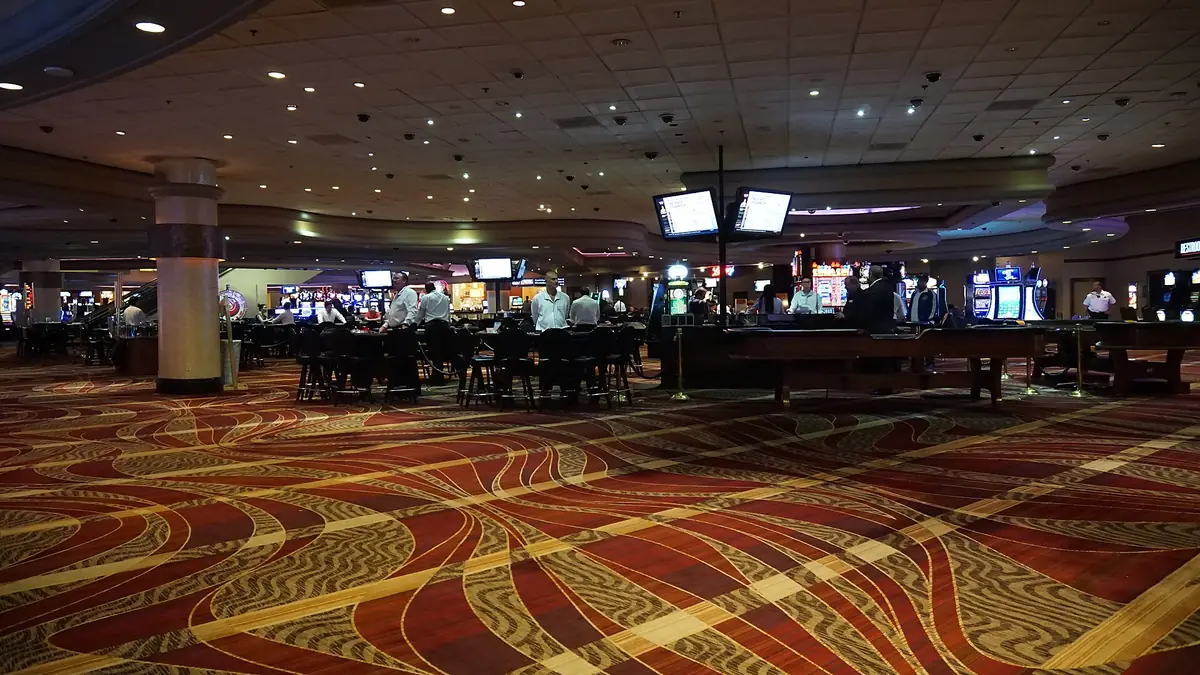 Wide view of a casino gaming floor with tables and patterned carpet